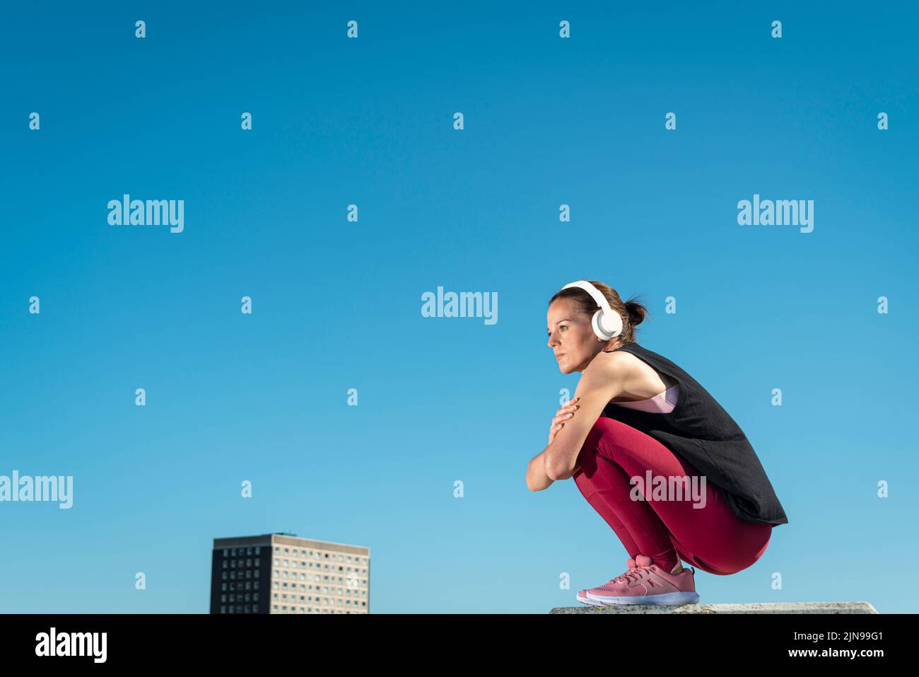 Woman wearing headphones and listening to music, urban setting. Stock Photo