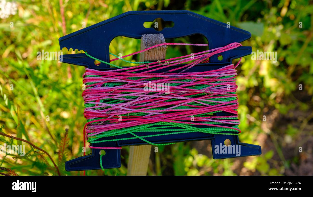 Colorful garden string on a spool and scissors with orange handles hung