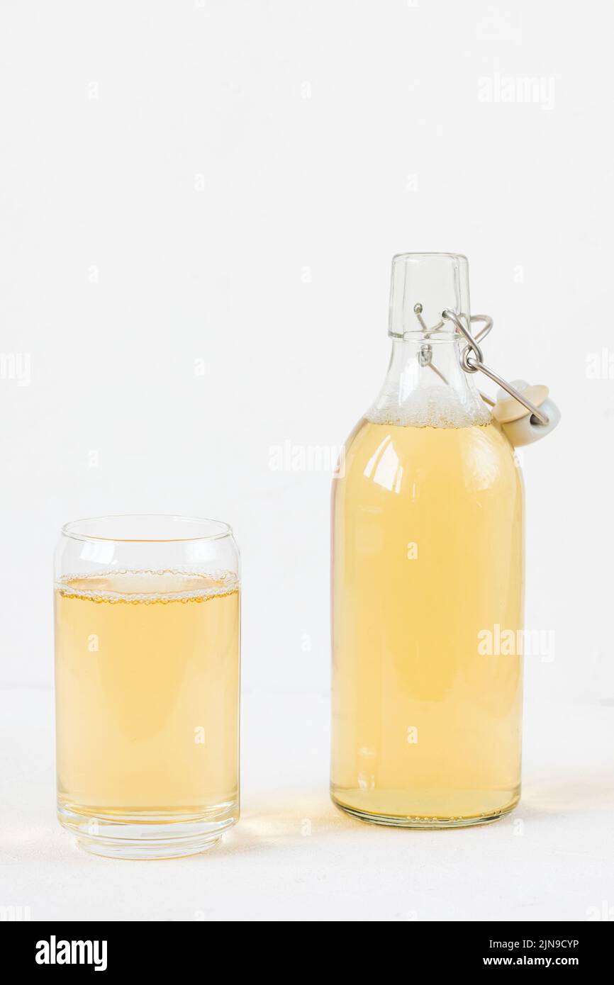 Homemade kombucha fermented drink in glass and bottle on white