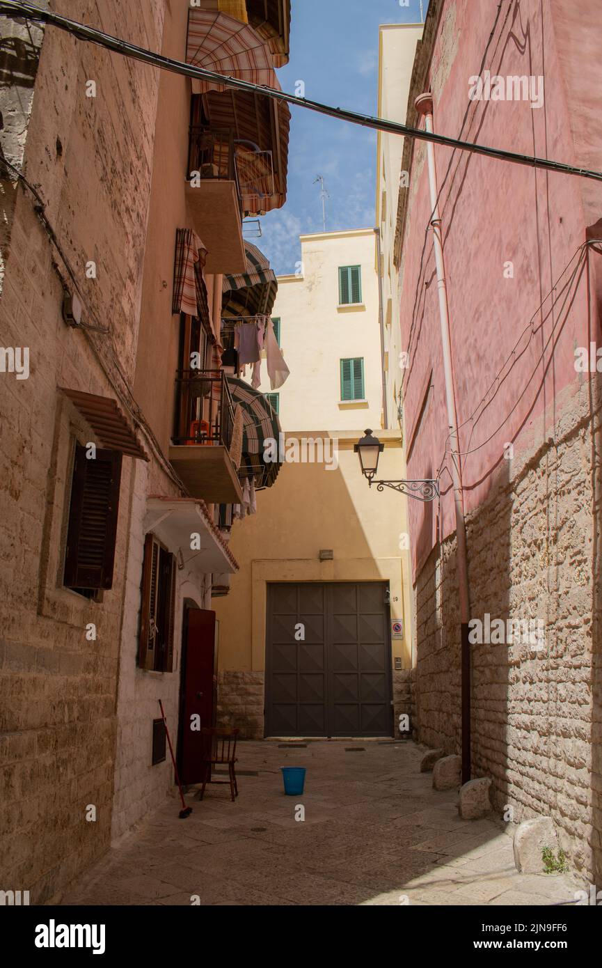 Alleyway in Bari old Town with strong sun and sharp shade, typical stone buildings, balconies and cobblestones Stock Photo