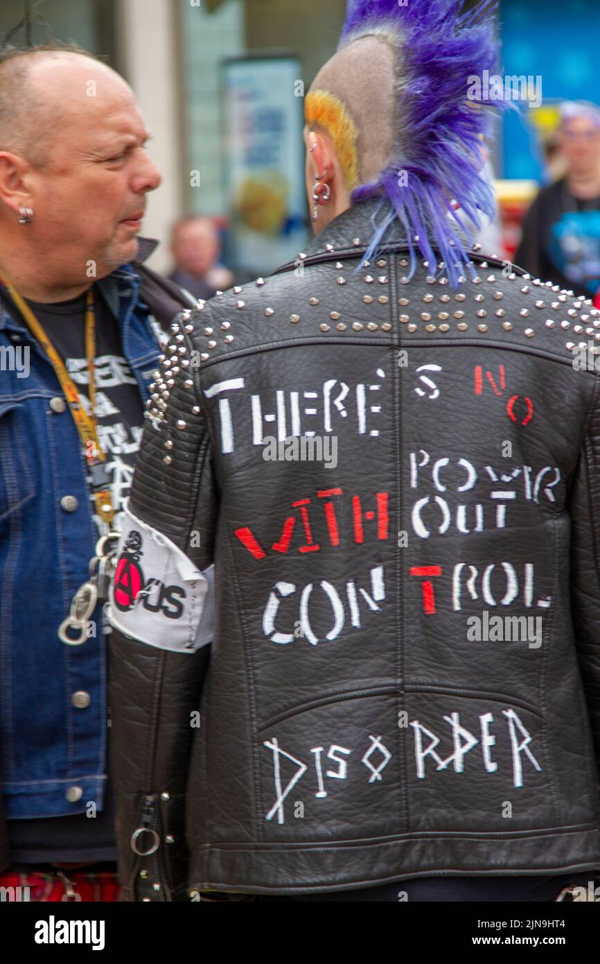 There's no power without control leather studded jacket. The punk subculture, ideologies, fashion, with Mohican dyed hairstyles and colouring at the 2022 Punk Rebellion festival at The Winter Gardens, Blackpool, UK. A protest against conventional attitudes and behaviour, a clash of anti-establishment cultures,  mohawks, safety pins and a load of attitude at the seaside town as punks attending the annual Rebellion rock music festival at the Winter Gardens come shoulder to shoulder with traditional holidaymakers. Stock Photo