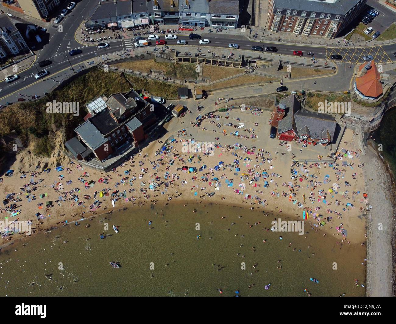 An aerial view of people enjoying the hot weather on the beach at Cullercoats Bay in North Tyneside. The Met Office has issued an amber warning for extreme heat covering four days from Thursday to Sunday for parts of England and Wales as a new heatwave looms. Picture date: Wednesday August 10, 2022. Stock Photo