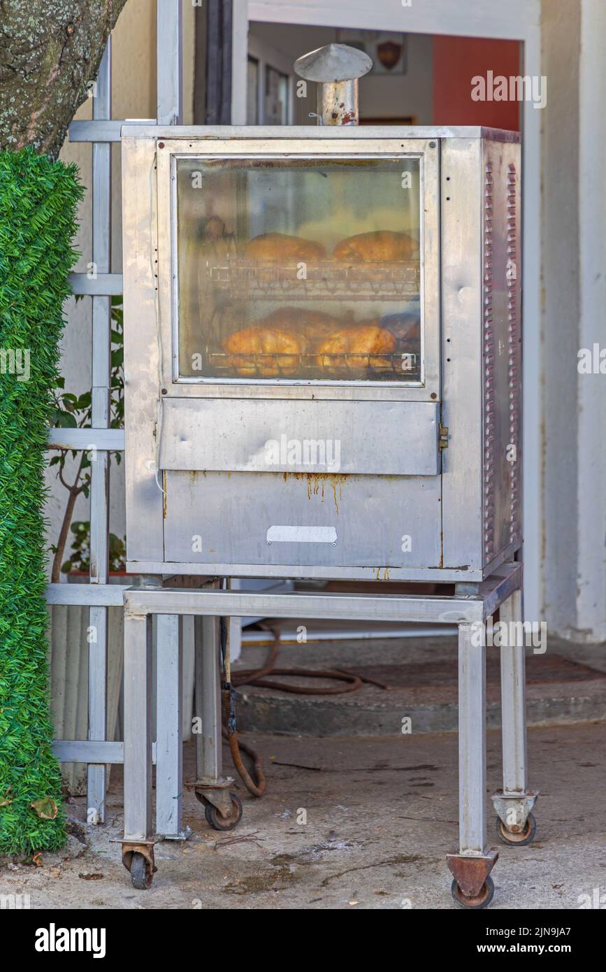 Commercial Chicken Rotisserie Roasting Machine in Front of Restaurant Stock Photo