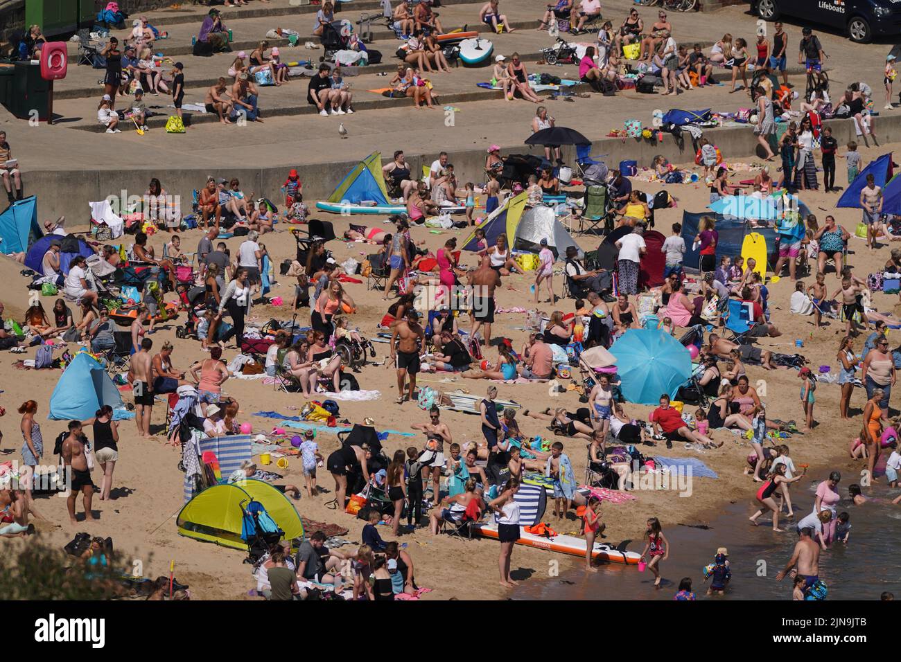 An aerial view of people enjoying the hot weather on the beach at Cullercoats Bay in North Tyneside. The Met Office has issued an amber warning for extreme heat covering four days from Thursday to Sunday for parts of England and Wales as a new heatwave looms. Picture date: Wednesday August 10, 2022. Stock Photo