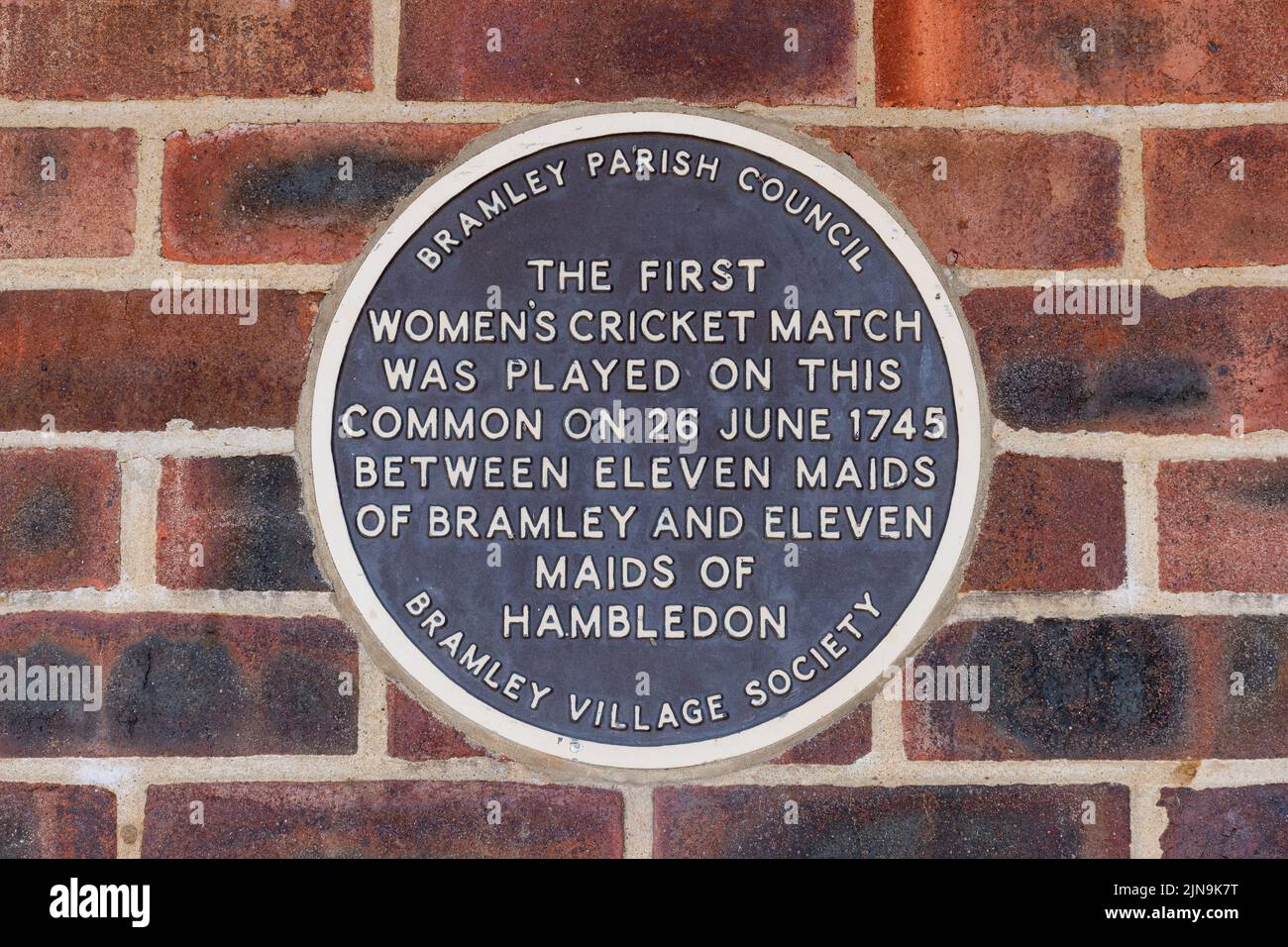 Plaque commemorating the first women's cricket match in 1745 on Bramley Village cricket club building, Gosden Common, Surrey, England, UK Stock Photo