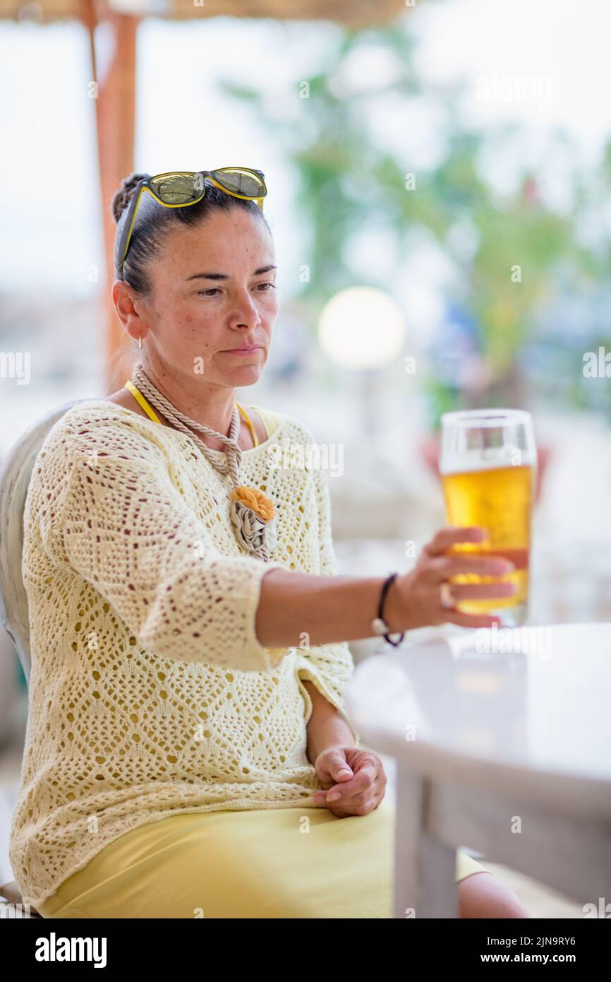 Portrait of woman drinking beer at beach cafe Stock Photo