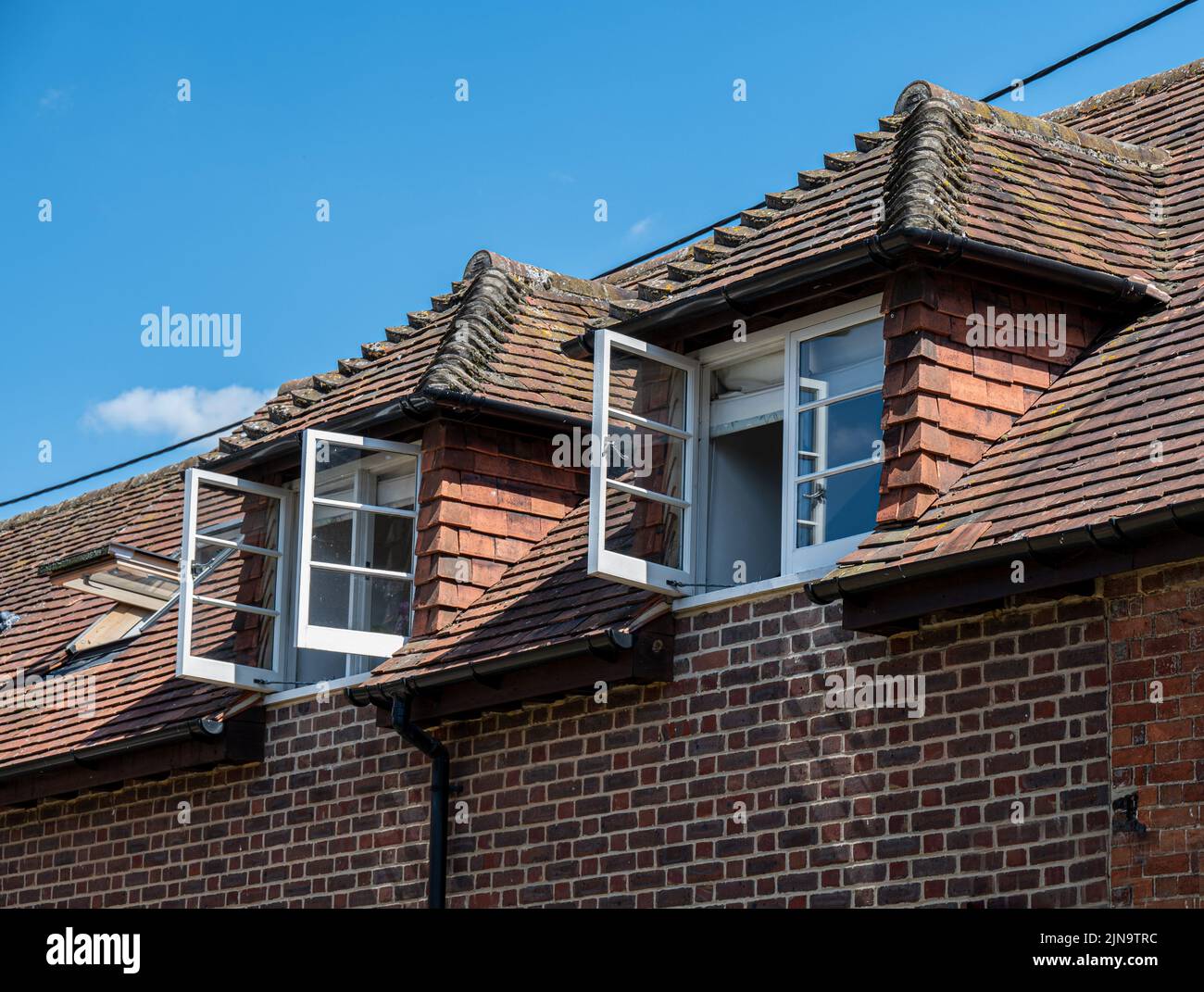 Open upper floor windows on a hot sunny day to allow a cool breeze to blow through Stock Photo