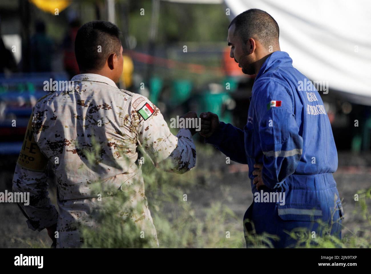 Member of security forces and of the rescue team bump their fists as they participate in the rescue operation for miners trapped in a coal mine that collapsed in Sabinas, in Coahuila state, Mexico, August 10, 2022. REUTERS/Luis Cortes Stock Photo