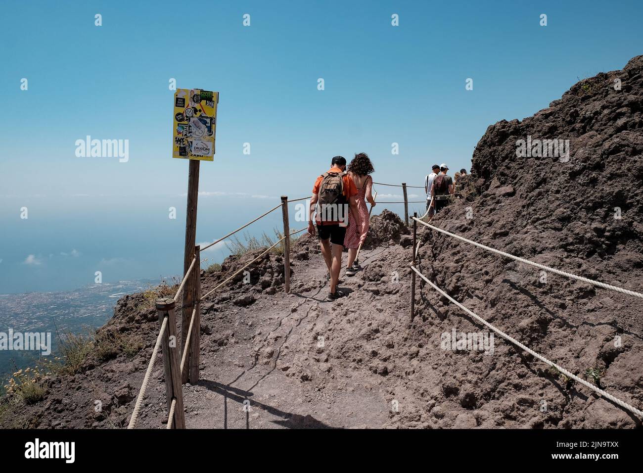 Tourist walk along the path around the top of the cone of Mount Vesuvius Italy with the amazing view across the Naples area to the left. Stock Photo