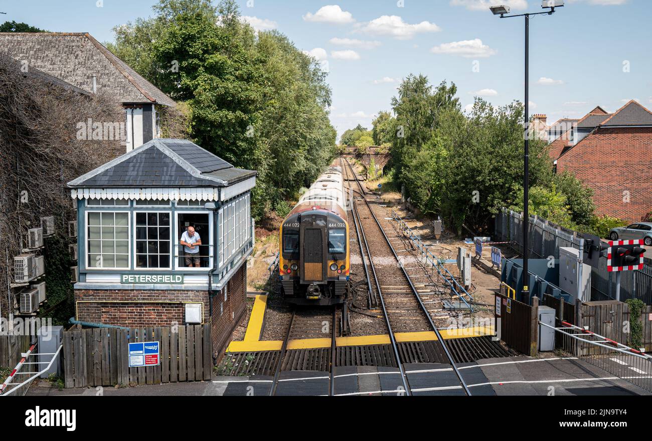 Train departing Petersfield station along side the signal box Stock Photo