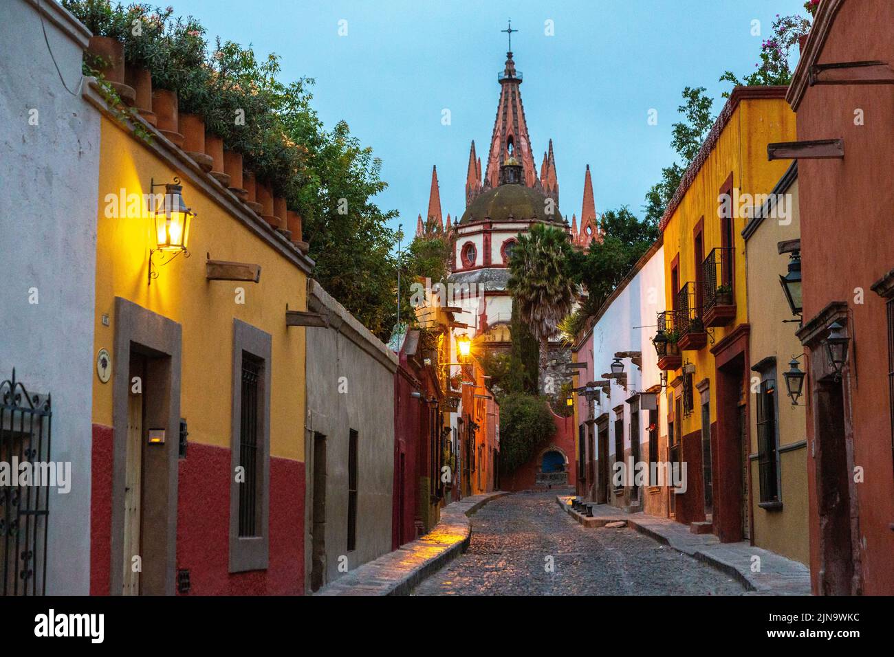 Early morning view of the cobblestone Calle Aldama of the original barque tower of Parroquia de San Miguel Arcangel in the historic city center of San Miguel de Allende, Mexico. Stock Photo