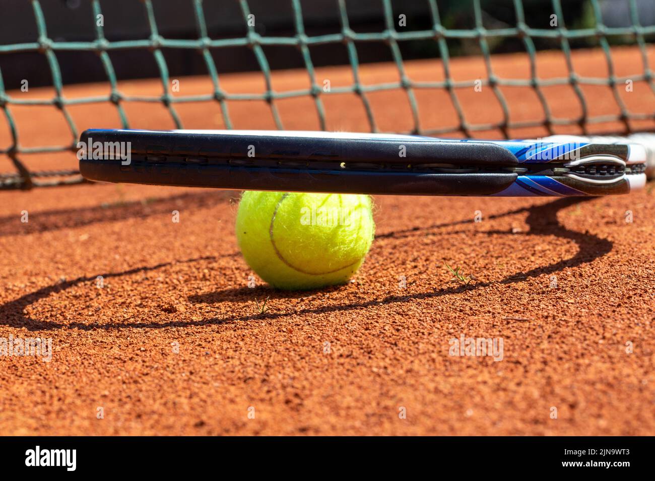 Symbol image tennis: Close-up of a tennis ball and tennis racket on a clay court Stock Photo