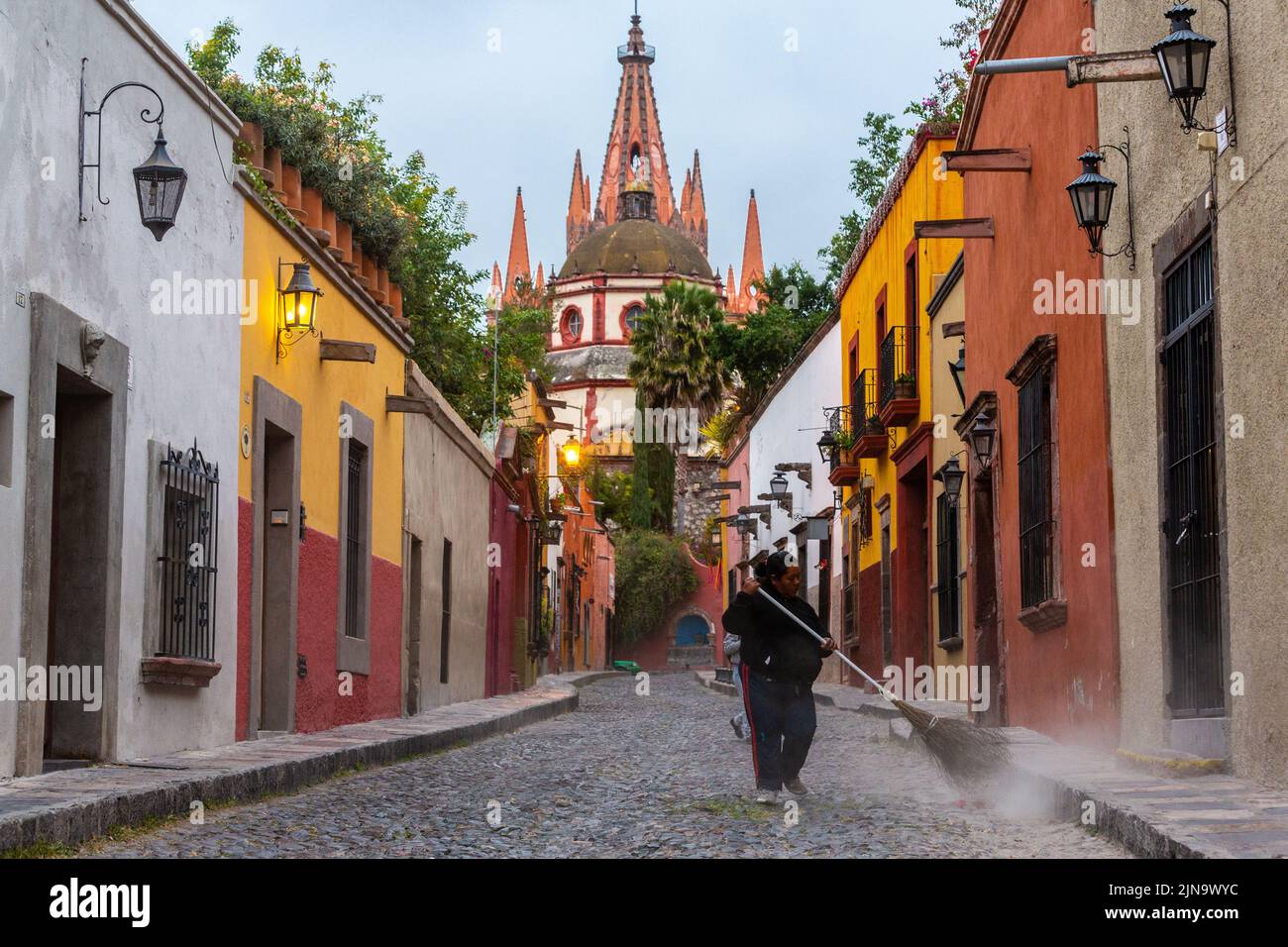 A street cleaner sweeps the cobblestone streets of Calle Aldama early morning in the historic city center of San Miguel de Allende, Mexico. Stock Photo