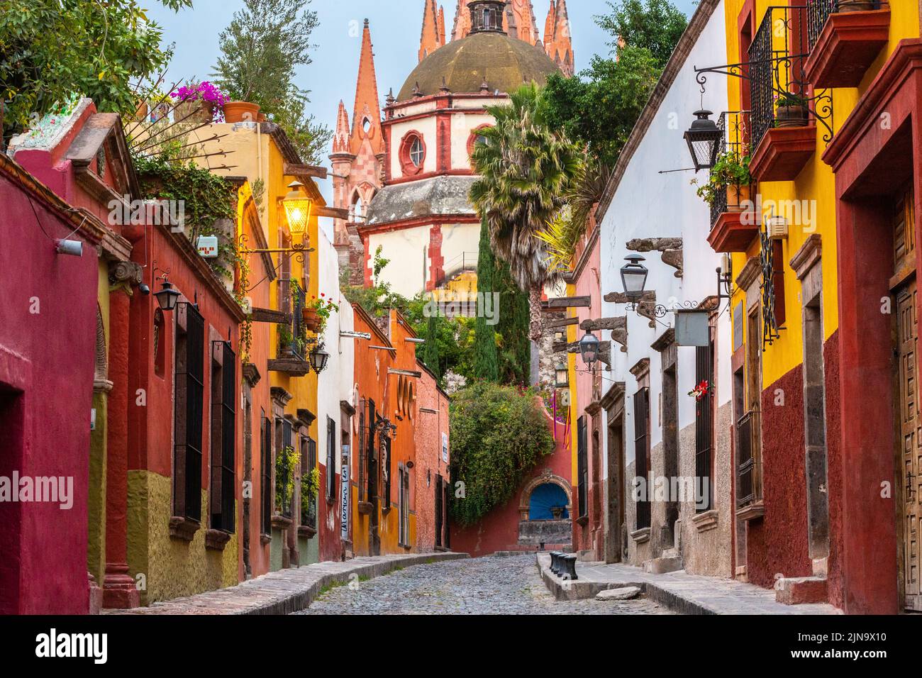 Early morning view of the cobblestone Calle Aldama and the original barque tower of Parroquia de San Miguel Arcangel in the historic city center of San Miguel de Allende, Mexico. Stock Photo
