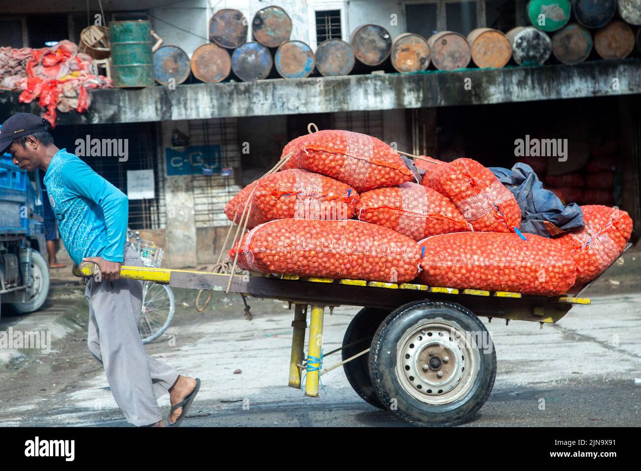 Yangon. 10th Aug, 2022. A man hauls a two-wheeled cart carrying onion bags at a wholesale market street in Yangon, Myanmar on Aug. 10, 2022. Credit: Myo Kyaw Soe/Xinhua/Alamy Live News Stock Photo