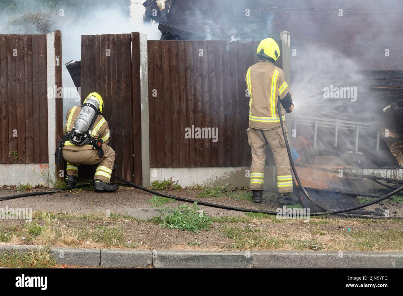 Essex Fire and Rescue Service firefighters in protective clothing dangerous & hazardous work on house fire working with breathing apparatus England UK Stock Photo