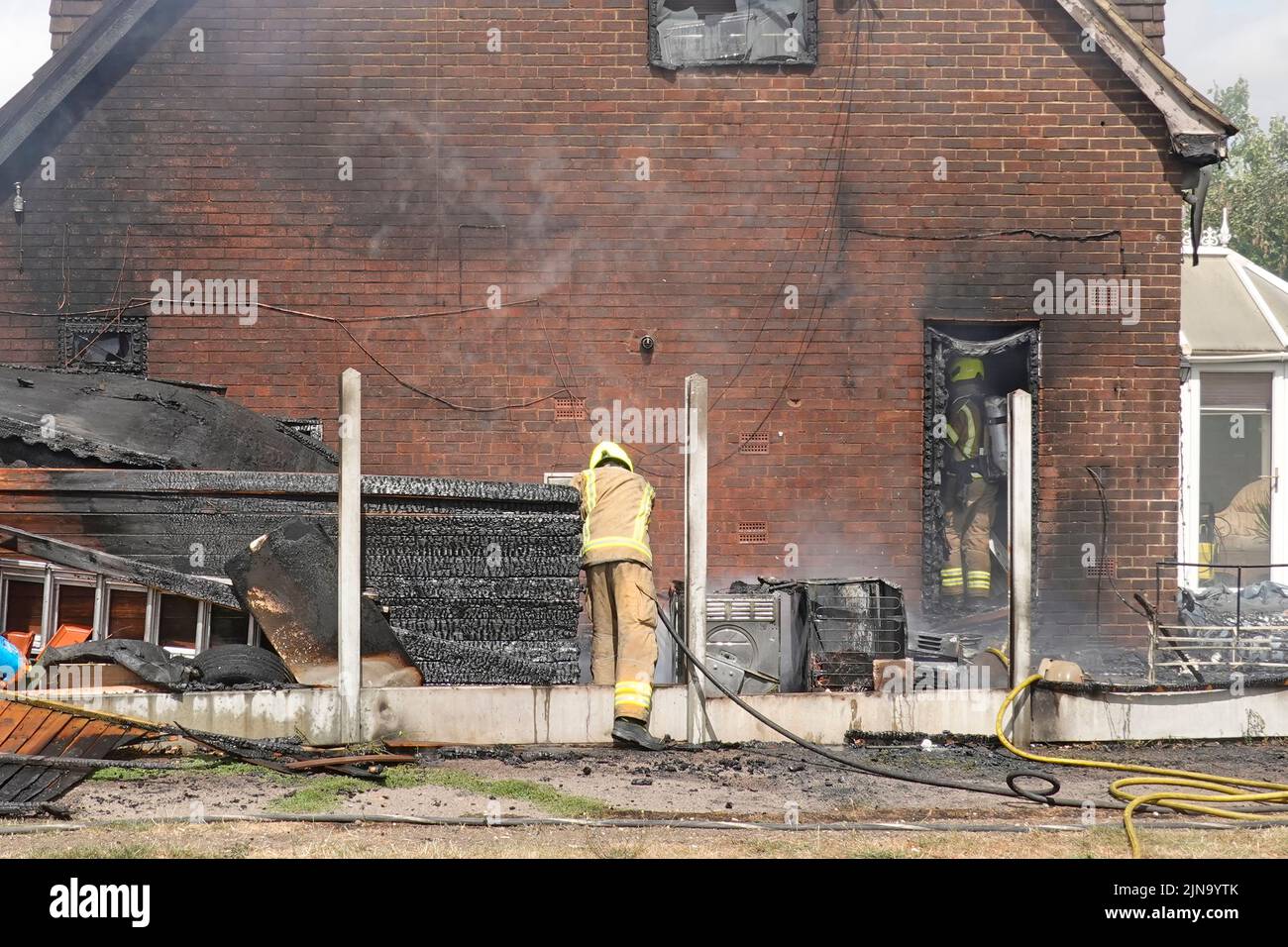 Essex Fire and Rescue Service firefighter in protective clothing dangerous & hazardous work indoor search damping down aftermath house fire England UK Stock Photo