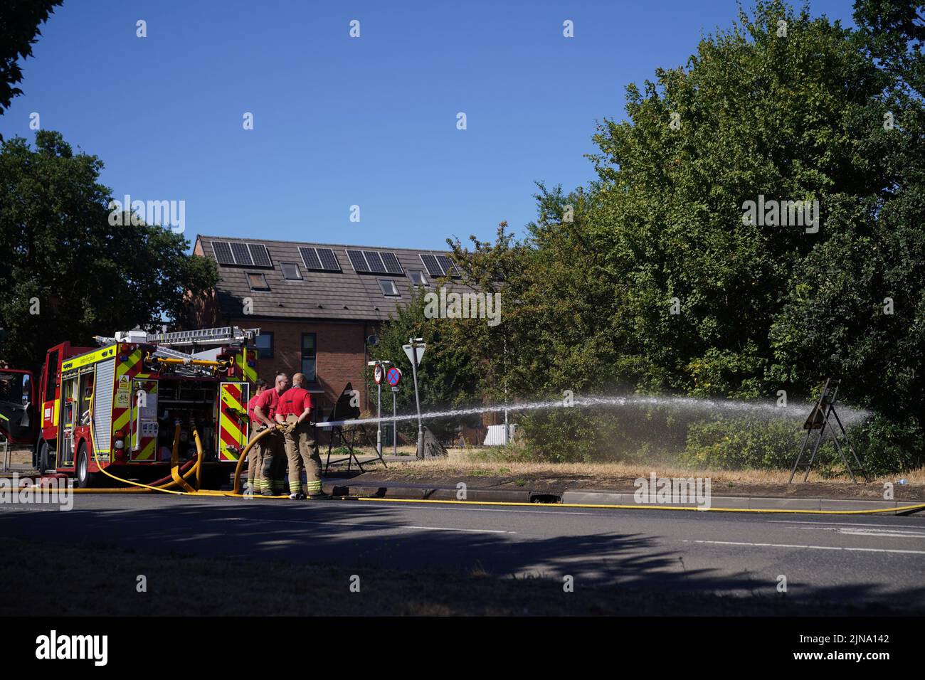 London Fire Brigade dealing with the aftermath of a grass fire in Rainham, east London. The Met Office has issued an amber warning for extreme heat covering four days from Thursday to Sunday for parts of England and Wales as a new heatwave looms. Picture date: Wednesday August 10, 2022. Stock Photo