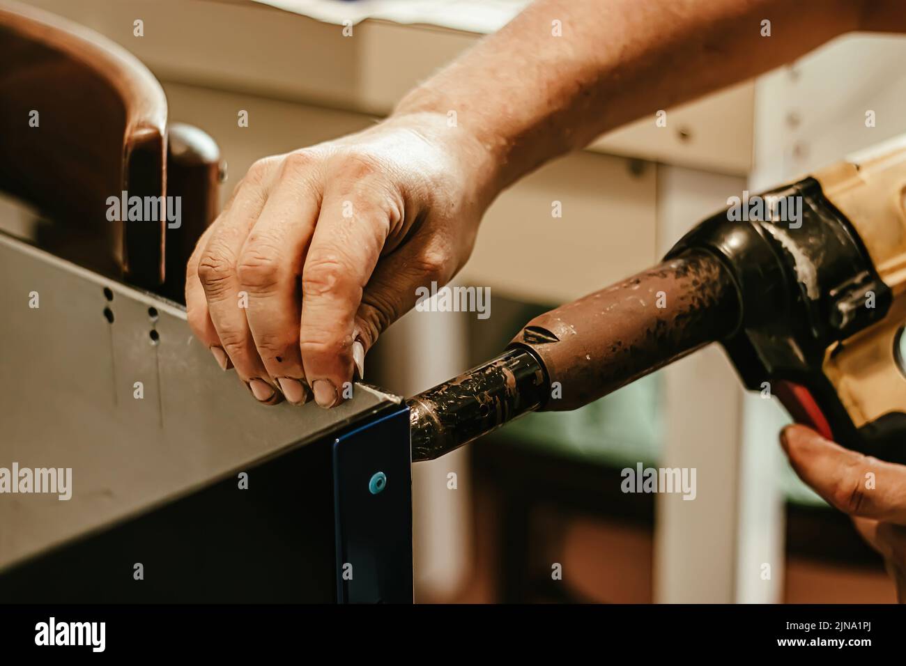 Male worker uses electric riveting gun. Hand holding riveting machine