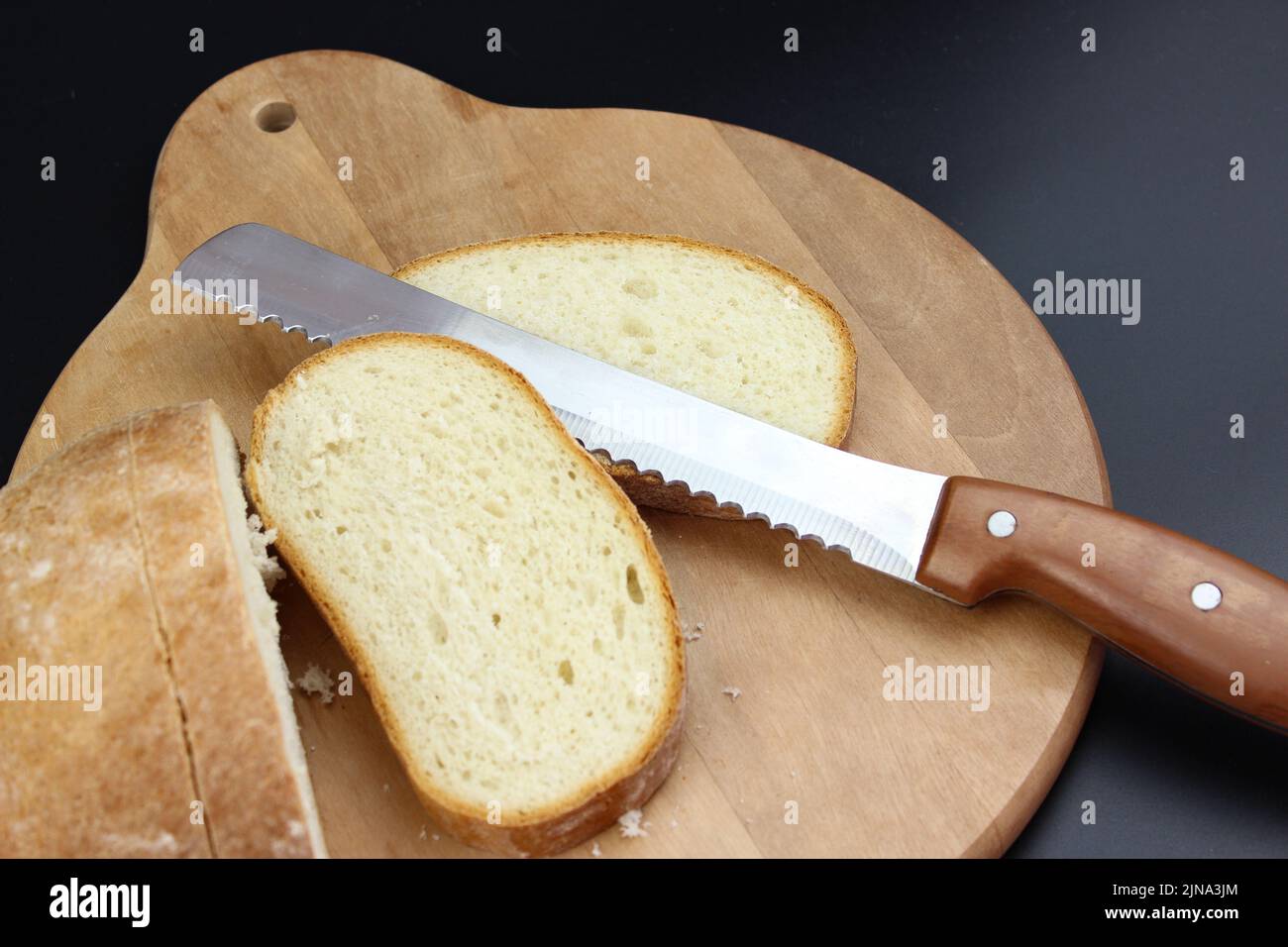 Bread knife cut fresh, crispy, rye bread. Slicing delicious bread Stock Photo