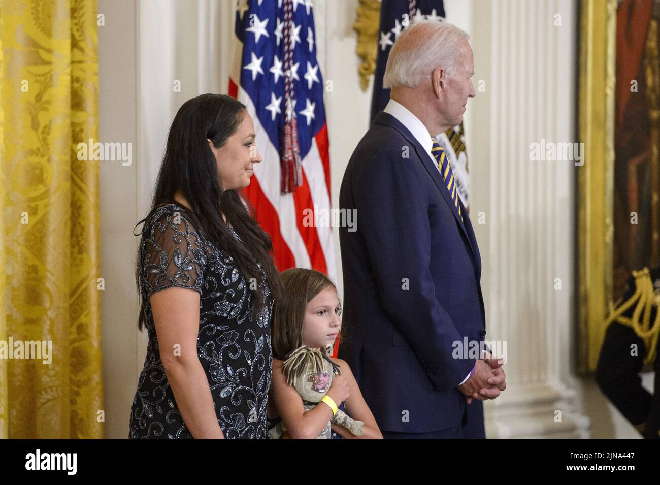 Washington, United States. 10th Aug, 2022. Danielle Robinson, wife of Sgt. First Class Heath Robinson, and Brielle, their daughter, stand next to President Joe Biden during a signing ceremony for the PACT Act of 2022, a bill to expand health care benefits for veterans exposed to toxic burn pits, in the East Room of the White House in Washington, DC on Wednesday, August 10, 2022. Photo by Bonnie Cash/UPI Credit: UPI/Alamy Live News Stock Photo