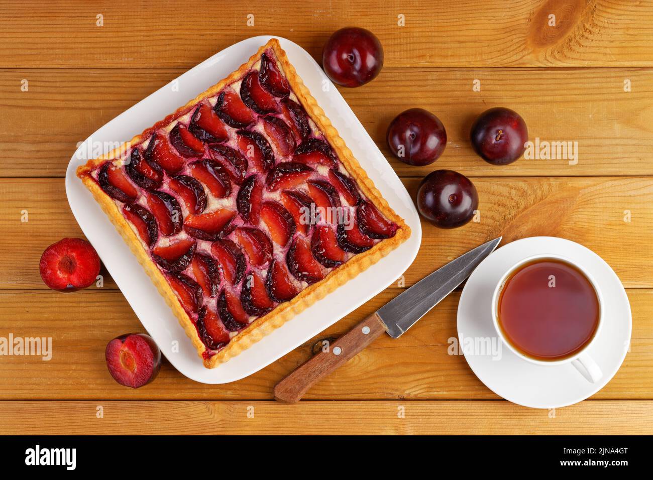 Homemade plum cake and cup of tea on wooden table. Top view. Stock Photo