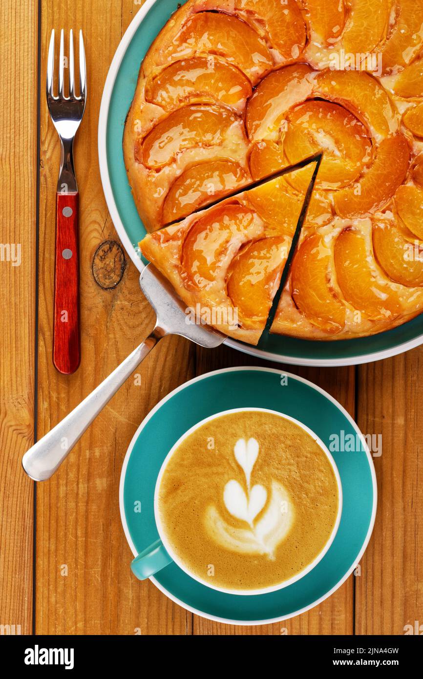 Closeup homemade pie with peaches and cup of coffee on wooden table. Top view. Stock Photo