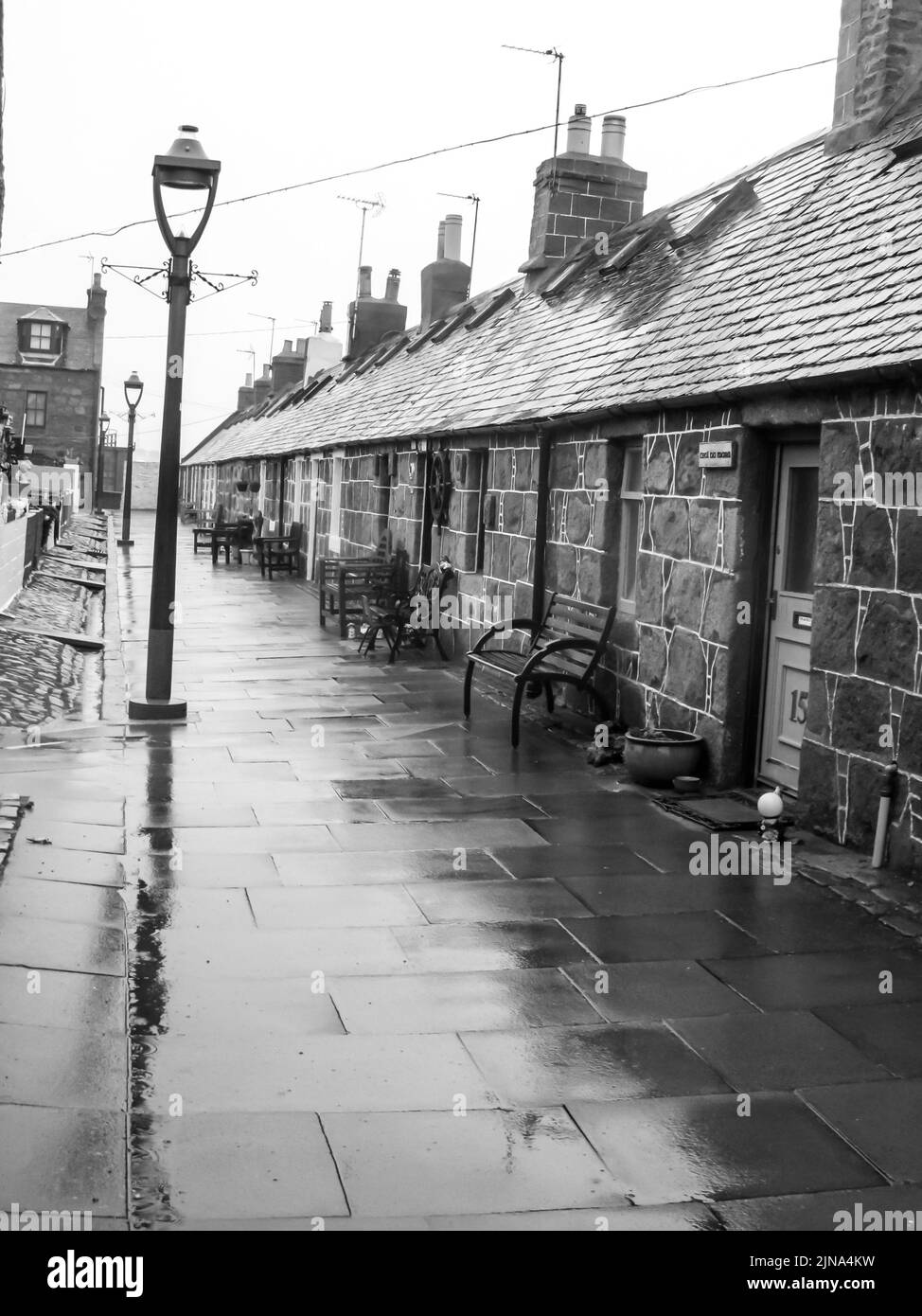 The small quaint old fishing village of Footdee, in the city of Aberdeen, Scotland, in black and white on a cold rainy day. Footdee, localy known as F Stock Photo