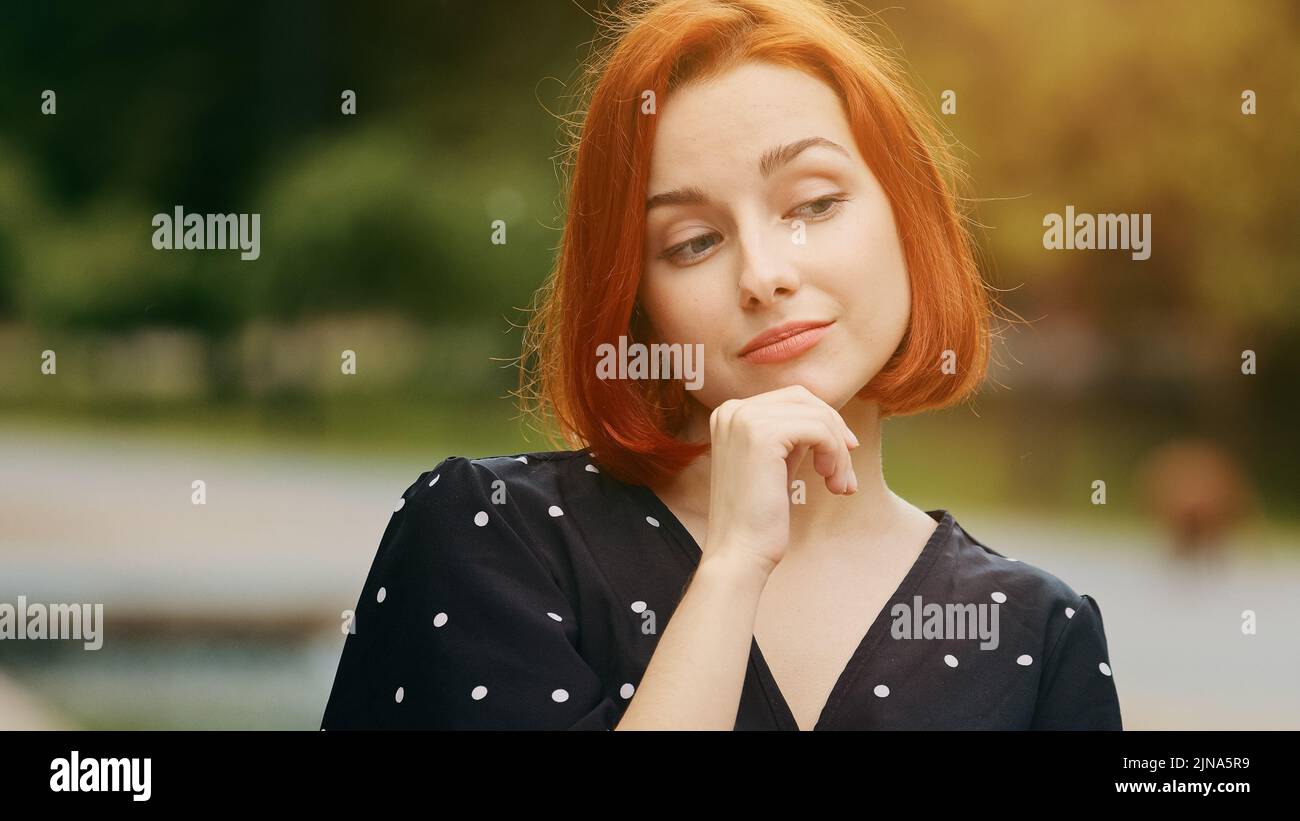 Caucasian thoughtful creative woman redhead young girl student thinking choose ponder planning holds hand to chin makes finger up excited with good Stock Photo