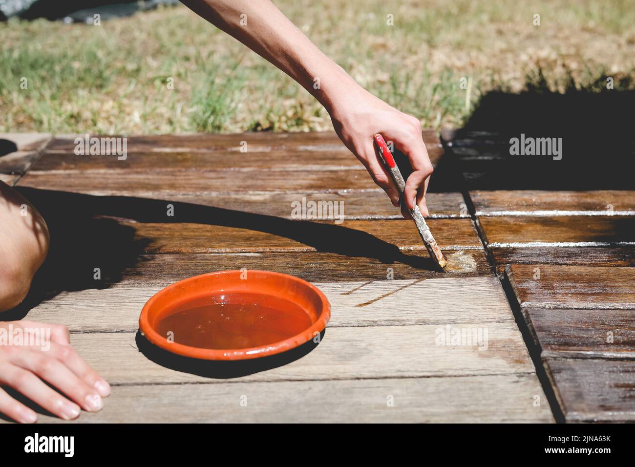 Close-Up of a person varnishing wooden decking in summer Stock Photo