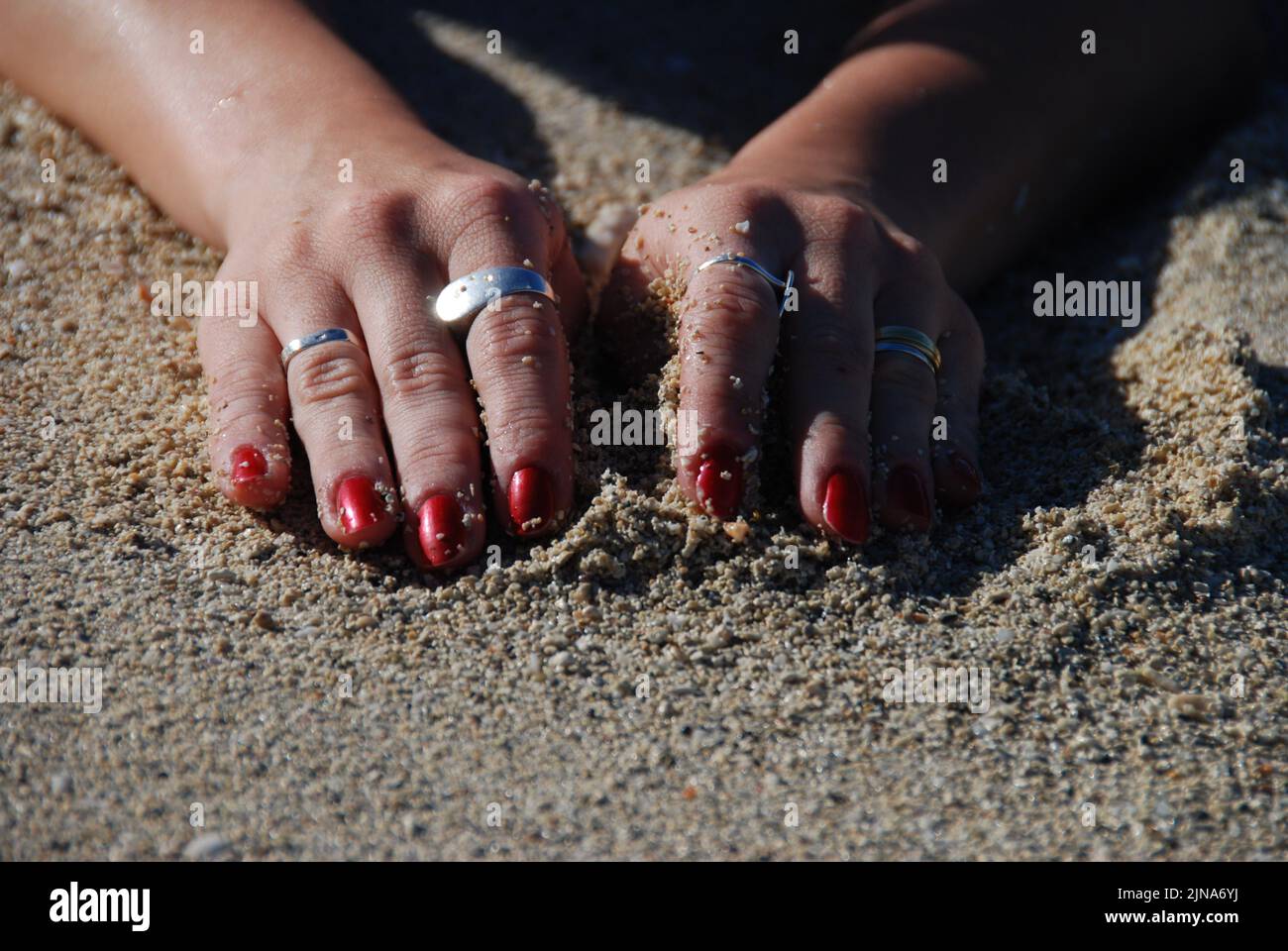 Close-Up of a woman's hands in the sand on a beach Stock Photo