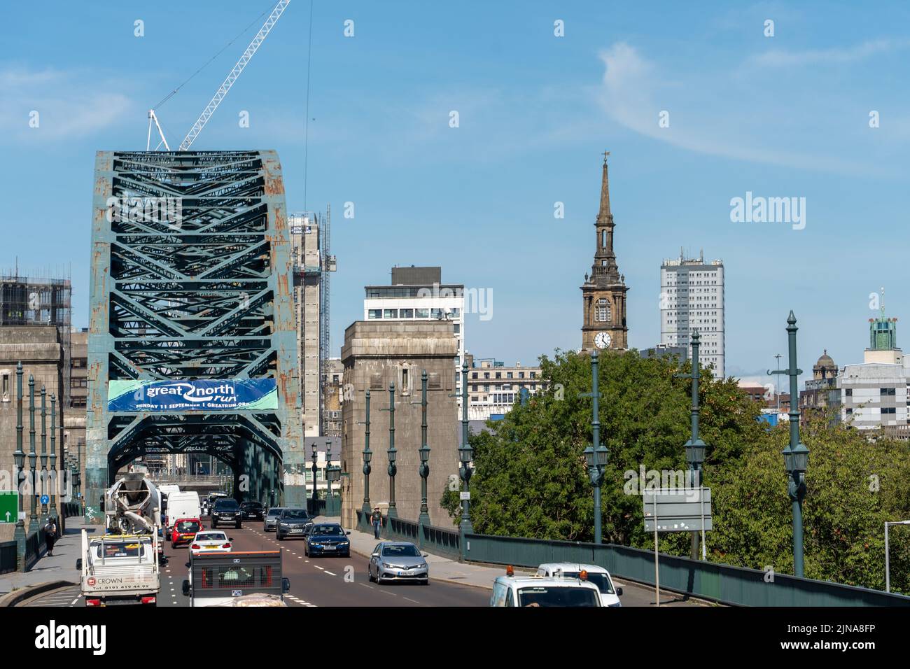 Cityscape view of the Tyne Bridge crossing from Gateshead to Newcastle upon Tyne, UK, including the spire of the St Mary' visitor centre. Stock Photo