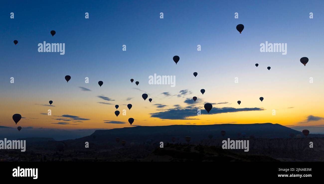 hot air balloons take off at sunrise over the city of goreme in turkey Stock Photo