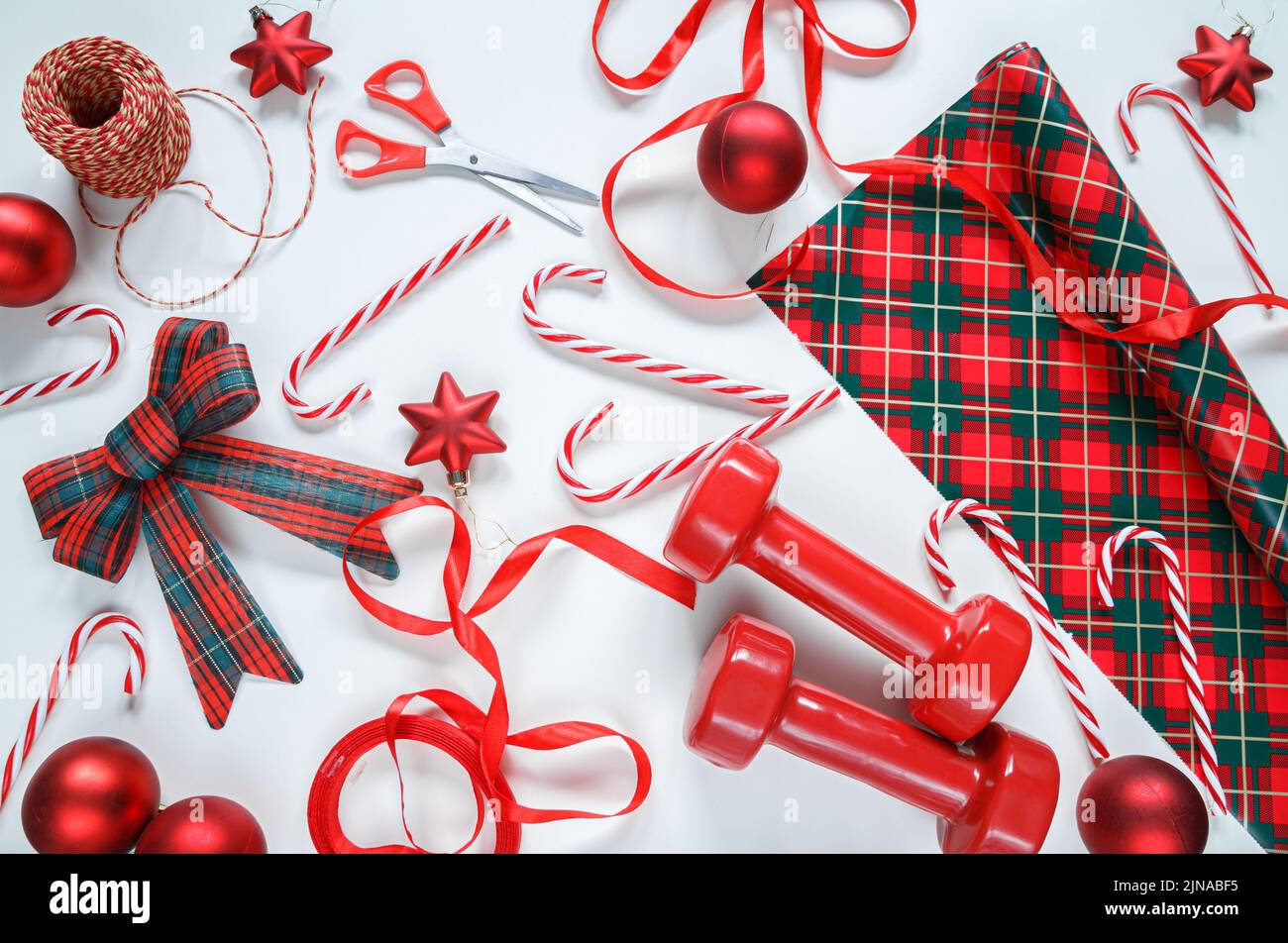 Dumbbells and gift wrapping paper, string, ribbon bow, candy canes, scissors and decorative