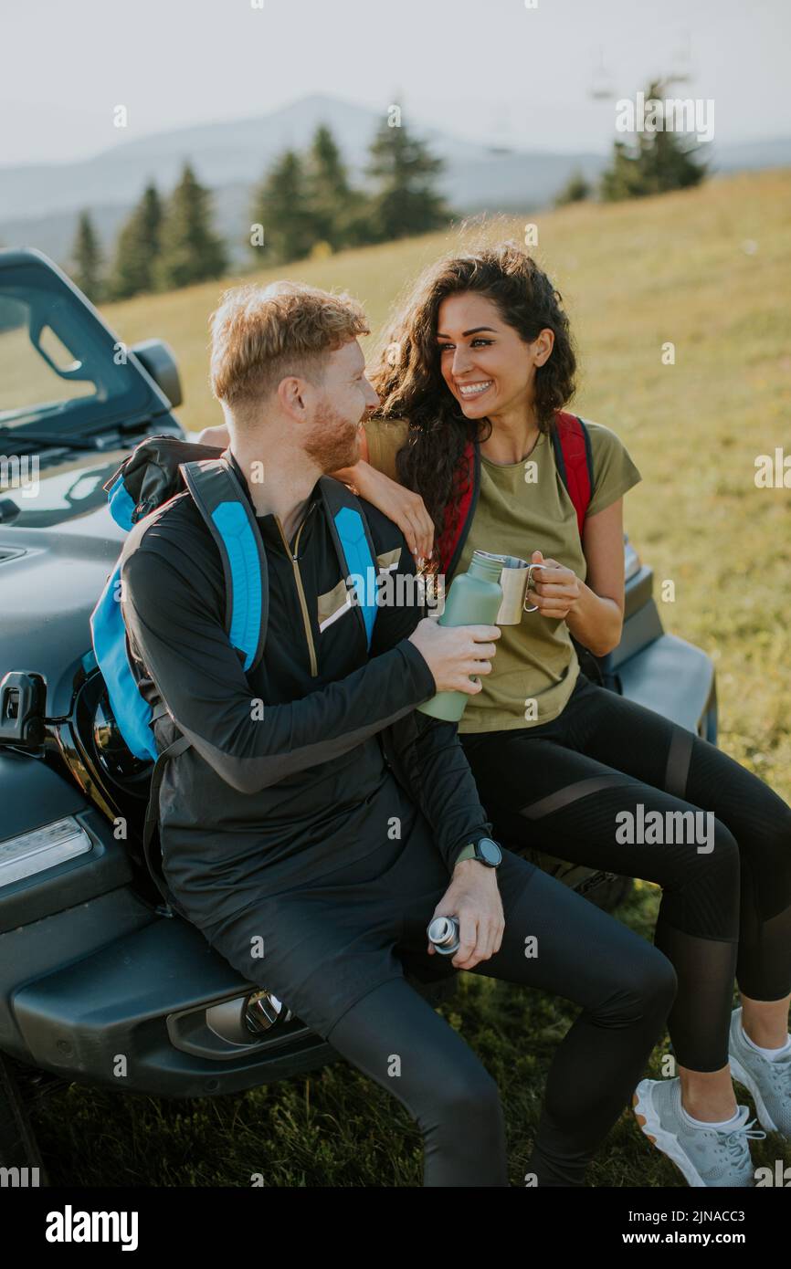 Handsome young couple relaxing on a terrain vehicle hood at countryside Stock Photo