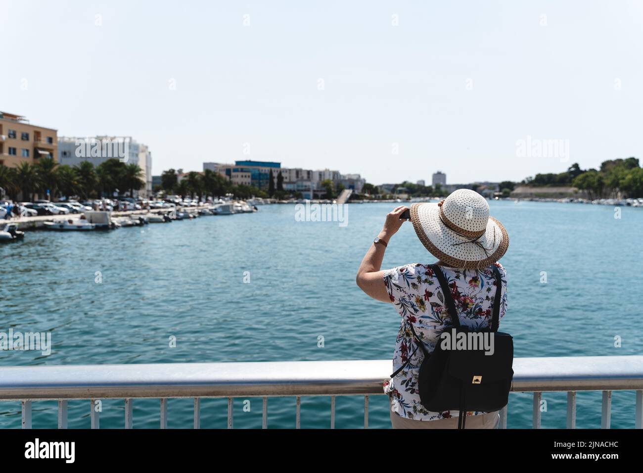 Zadar, Croatia - 26 July 2022: Rear View Of A Woman Taking Photos Of The City With Her Camera During Summer Vacation In The City Of Zadar In Croatia. Stock Photo