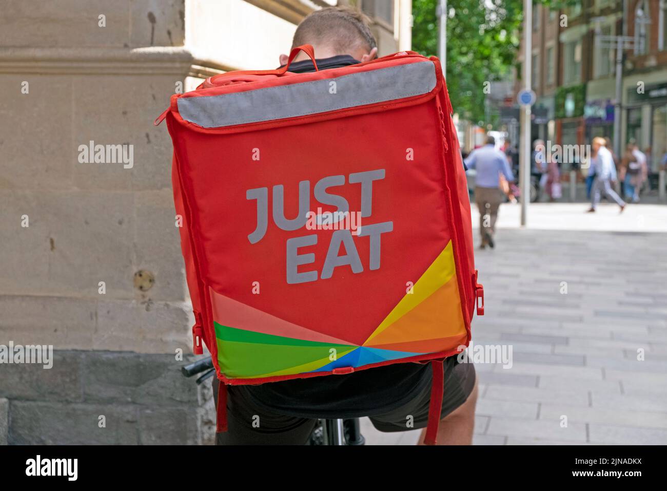 Just Eat fast food sign logo on back of rucksack on cyclist man courier delivery bike  in Cardiff City street Wales UK   KATHY DEWITT Stock Photo