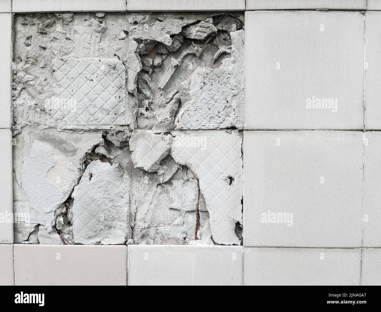 A wall with a broken off gray tile from the wall in full screen Stock Photo