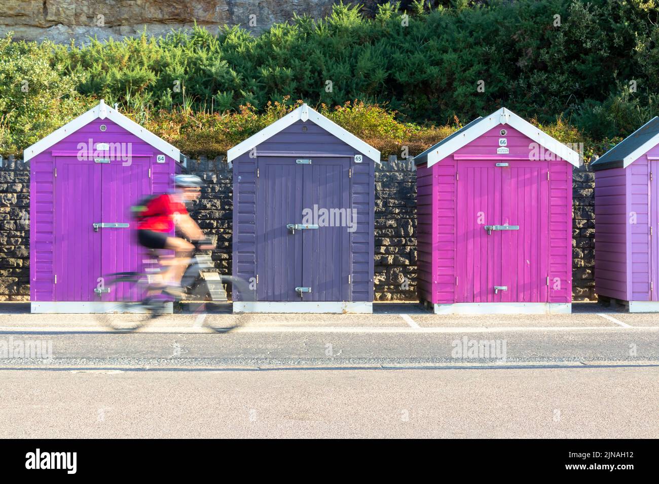 row of multicoloured purple wooden beach huts by the sea with blurred