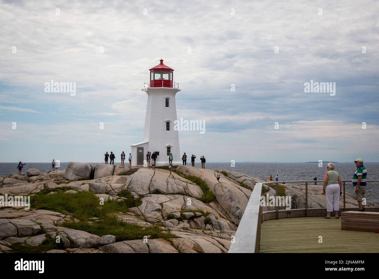 People walk around Peggy's Cove lighthouse in Peggy's Cove, Nova Scotia