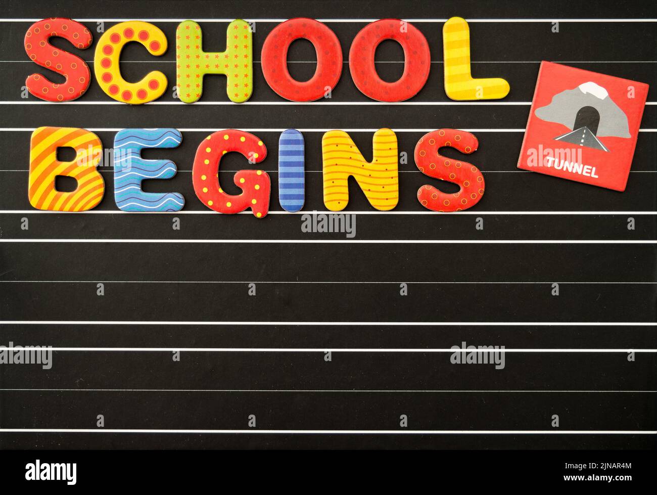 Back to school concept with colorful magnetic letters on a chalkboard as a black background. There is a free text field. Stock Photo