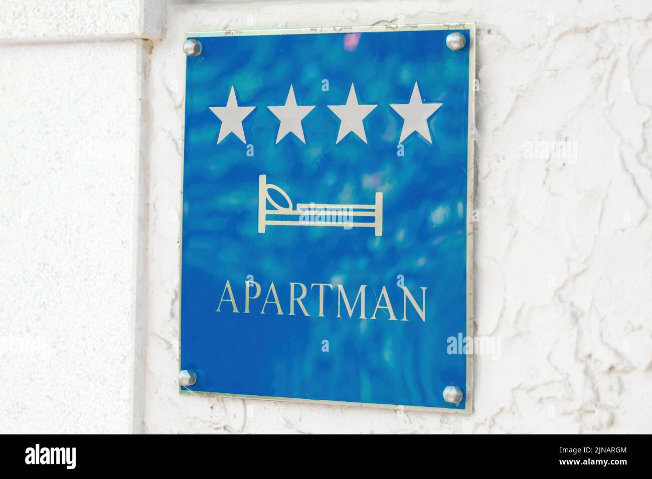 Blue sign with silver stars and inscription in capital letters hanging on wall. Resort hotel receives tourists offering apartments Stock Photo
