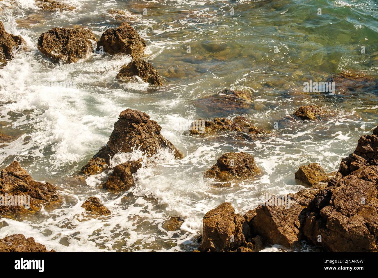 Small ocean waves crashing of rocks on shallow coastline at high tide ...