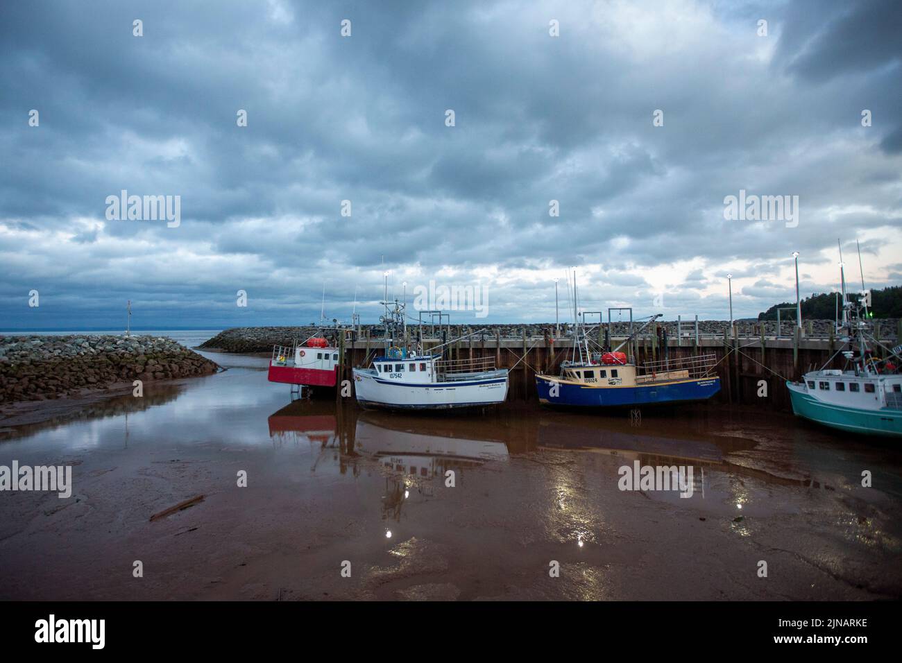 Lobster fishing boats sit on the ocean floor in harbour in Alma, New