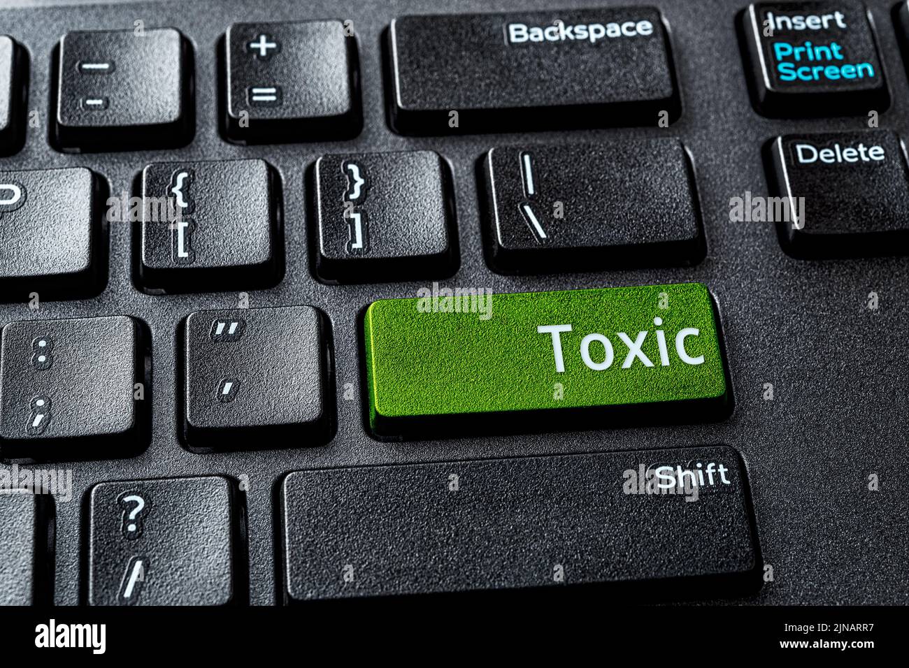 Toxic word on the green enter key of a desktop pc keyboard. Concept of toxic relationship on the Internet. Destructive online communication. Stock Photo