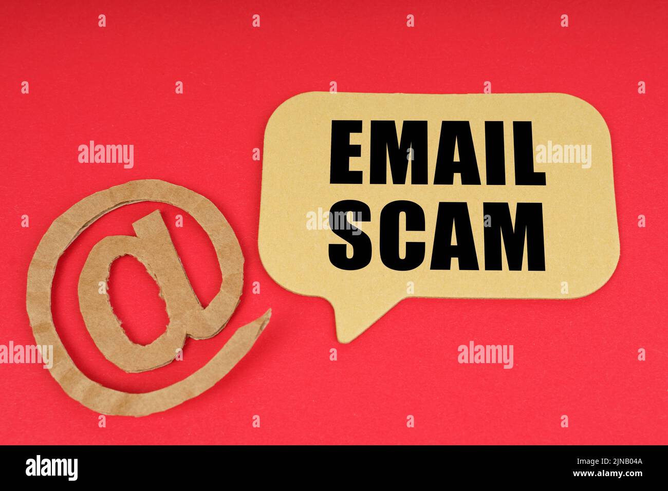 Email and business. On a red surface, a symbol and a sign with the inscription - EMAIL SCAM Stock Photo