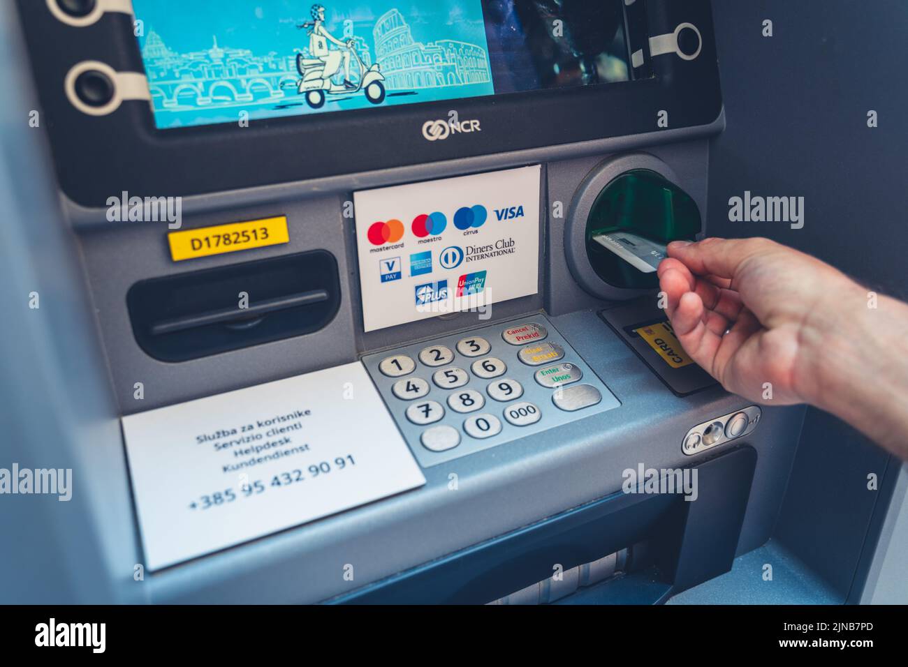 Croatia - 26 July 2022: A Man Slides A Mastercard Credit Card Into An ATM To Withdraw Cash From His Account. Withdraw Money Abroad Stock Photo