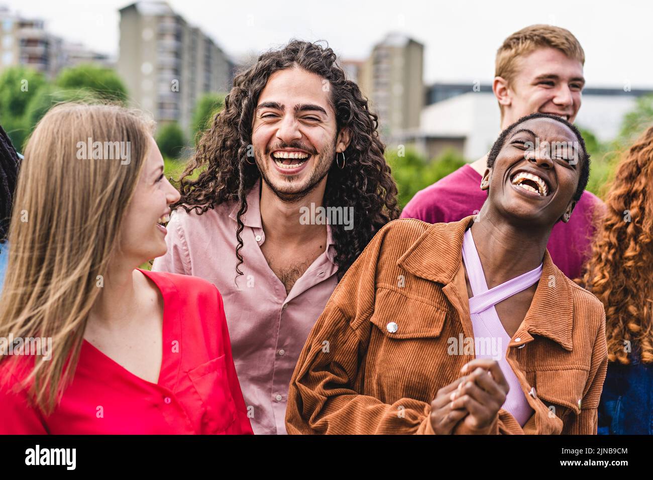 Multiethnic cheerful community of young friends gather outdoors and having fun laughing together - happy people lifestyle concept Stock Photo