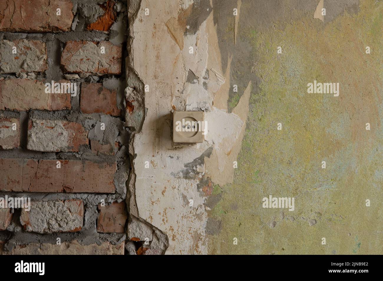 Old wall with a socket under renovation. Brickwork and old plaster