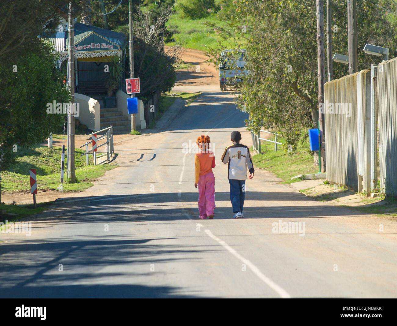 South Africa- August 26 2007; Two young people walking away down hill in rural area. Stock Photo